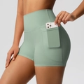 Detail view of high-waisted yoga shorts with side pocket holding a smartphone - S / Basil Green