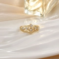 Elegant gold crown ring with hollow design and clear gemstones on a wavy surface - Intricate Hollow Crown (JZ0135)