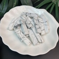 Macro shot of rectangular white marble stone beads with grey veins on a shell ceramic plate - White Turquoise
