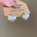 Close-up of heart-shaped pearl earrings on a brown kraft card holder for display - Silver Brushed Heart Hoop Earrings
