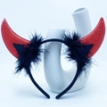 Close-up of red sequined devil horns with black feather trim on a white vase - Red Glitter Horn With Feathers