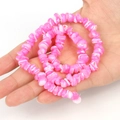 Hand holding irregular pink and white shell beads for DIY jewelry making and bracelets - Irregular Rose Red