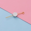 Primer plano de una cuenta hexagonal de acero en un pasador dorado para joyería DIY - Color Acero