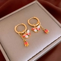 Detailaufnahme matter goldener Ohrringe mit Schmetterling und Tulpe auf Schmuckbox - Gold