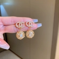 Close-up of gold earrings with pavé crystals, pearls, and hollow sphere details - Gold Letter Ball Dangle