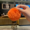 Orange plush pompom keychain in fluffy faux fur held in hand as a cute bag charm - Persimmon Plush Ball