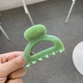 Detail of a light green glossy square hair claw clip held in hand with natural light - Leaf Green