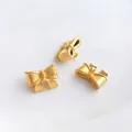 Dettaglio macro di ciondoli a fiocco in oro opaco per la creazione di gioielli - 12x9mm (Fiocco Oro Sabbia)