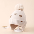 Detailed knit texture of off-white winter hat featuring embroidered bears and a faux fur pompom - 3-8 Years / Beige
