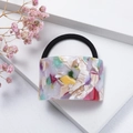 Close-up of acetic acid hair tie with colorful marble texture on minimalist white background - Colorful