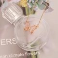 Dettaglio di una collana a farfalla dorata con cristalli rosa e piccoli zirconi - Rosa Pesca