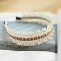 Détail d'un serre-tête bohème en dentelle avec broderies florales sur un livre - Blanc Cassé