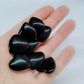 Piedras de obsidiana negra pulida en forma de corazón sostenidas en la mano pura - Negro