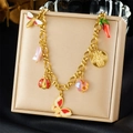 Detail view of a gold charm bracelet with enamel insect and floral pendants on a jewelry box - Insect Enamel Pendant Jewelry Set (N3555)