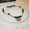 Collana con farfalla in acciaio argento con perle nere su un piatto bianco - Decorazione con Perline a Farfalla Nera