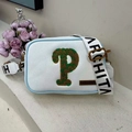 White canvas crossbody bag with green letter P patch and wide logo shoulder strap - White