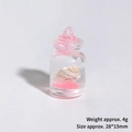 Gros plan d'une bouteille miniature avec un petit coquillage et du sable rose dedans - Bouteille Dérivante Lumineuse (Rose)