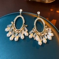 Close-up of vintage gold earrings with rhinestones, crystals and pearl tassels on a stand - Silver Needle - Gold Crystal Tassel Style