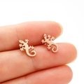 Detailed view of rose gold gecko stud earrings held to show compact animal design - Rose Gold