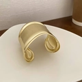 Détail d'un large bracelet jonc doré avec finition miroir polie sur un plateau blanc - Manchette Ouverte-Or