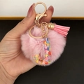 Detail of pink pompom keychain with resin letter J filled with colorful heart sequins - Letter J