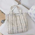 Close-up of floral floral patterns and 'simple wish' label on a beige canvas tote bag - Purple Striped Floral