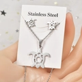 Détail d'un ensemble de bijoux tortue en acier inoxydable argenté avec motif géométrique - Tortue de mer