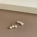 Detalle macro de tres elegantes perlas blancas en un pendiente de botón dorado minimalista - Pendientes de 3 perlas con pin de plata S925 / Blanco perla/Base dorada