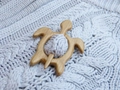 Close-up of a wooden turtle brooch pin fastening a light grey knitted fabric - Turtle