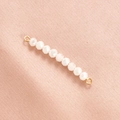 Macro shot of white faceted crystal beads with gold metal loops on pink fabric - Cream