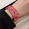 Wide gold cuff bracelet with pink gravel stones and pyramid studs in bohemian style - Rose Red