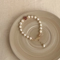 Close-up of baroque pearl bracelet with red gemstone and gold clasp on ceramic plate - Single Strawberry Crystal Pearl Bracelet