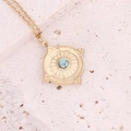 Macro view of a gold square pendant featuring a turquoise stone on a beige stone surface - 8# Turquoise