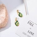 Detail of gold-plated leaf earrings with green enamel stripes on a stone display - Gold and Green Striped Oval Style (EH003)