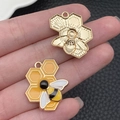 Detailed view of DIY gold alloy honeycomb and enamel bee charms held in hand - Honeycomb