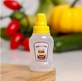 Mini bottiglia di miele spremibile con beccuccio giallo su vassoio in legno con verdure - HONTY Confezione Singola
