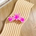 Drei pinke Farbverlauf-Haarklammern mit Blütenform auf hölzernem Untergrund - Dreifache siebenstrahlige Blüten / Rosenrot