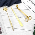 Golden stainless steel candle accessory set with trimmer, snuffer, and dipper on wood - Gold 3-Piece Candle Tool Set