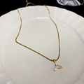 Elegante Halskette mit goldener Walflosse und funkelnden Zirkonia auf einem Keramikteller - Strass Goldener Fischschwanz-Stil