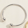 Detailopname van een minimalistische zilveren open armband met gladde metalen bolvormige uiteinden - Koperen Kralen Armband Witgoud Stijl (SL0194-1)