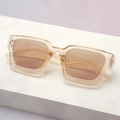 Close-up of thick champagne square frame sunglasses with brown lenses on a display stand - Champagne Frame / Tea Lens