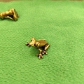 Figura de rana vintage en bronce macizo con textura realista sobre tela verde - Postura de rana dardo