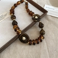 Detailed close-up of amber acrylic beads and gold spacers on a textured linen background - Necklace-Coffee