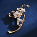 Detail shot of golden floral brooch with sparkling rhinestones on blue fabric - Abstract Floral
