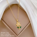 Macro shot of gold floral necklace with pink petals and green leaf in jewelry box - Pink Flower Pendant Style (C348钛钢链条铜微镶吊坠)