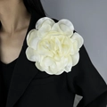 Close-up of a large cream fabric camellia flower brooch on a black blazer lapel - Beige