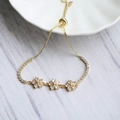 Dettaglio ravvicinato di un bracciale dorato regolabile con fiori in zircone lucenti - Bianco