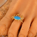 Golden crab ring with blue stone inlay and spiral band on a beach sand background - Blue Crab (4730)