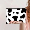 Close-up of cow print canvas makeup bag held by hand featuring a black zipper top - Black and White Cow Print Style (jiayingpbb0159)