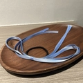 Detail view of a black elastic hair tie with a blue satin ribbon bow on a wooden tray - Blue